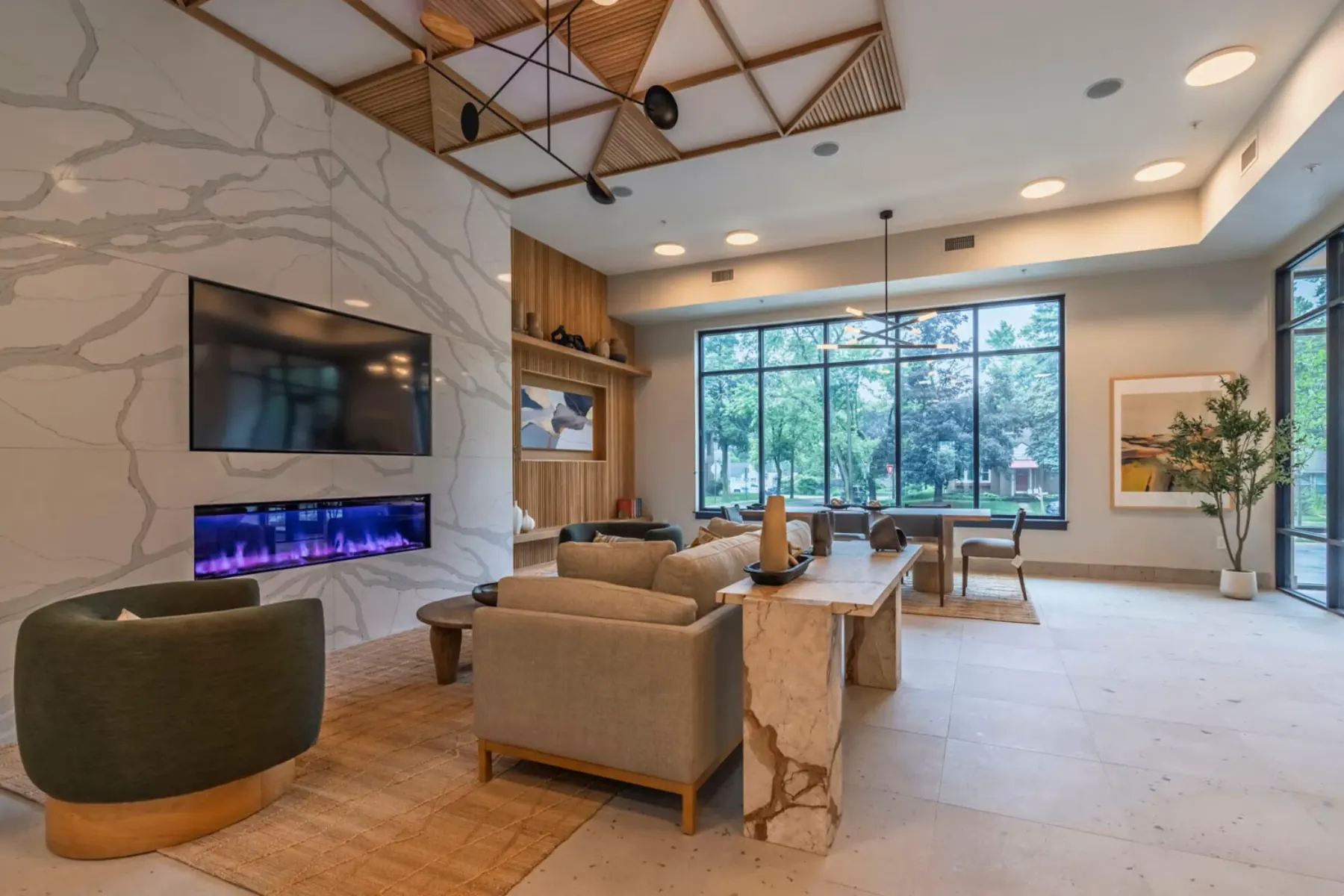 Resident lounge at Packard Row featuring a marble fireplace, modern seating, and a dining table beneath a sculptural pendant