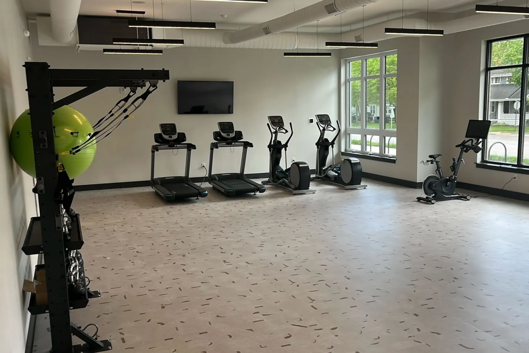Cardio section of the Packard Row fitness center with two treadmills, two ellipticals, and a Peloton-style spin bike