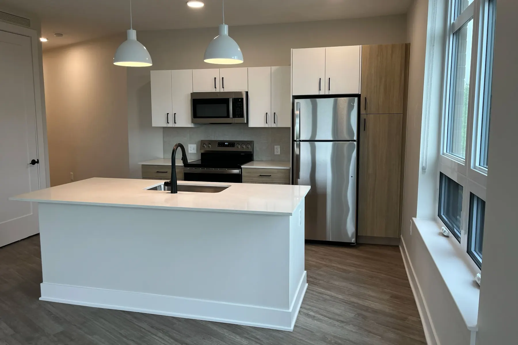 In-unit kitchen with white quartz island and stainless steel appliances